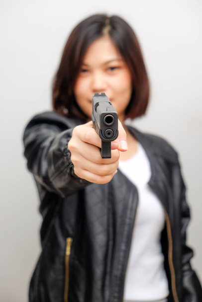 Black shirt women aiming gun to audience on white background, Defense personal trainning - Photo, Image