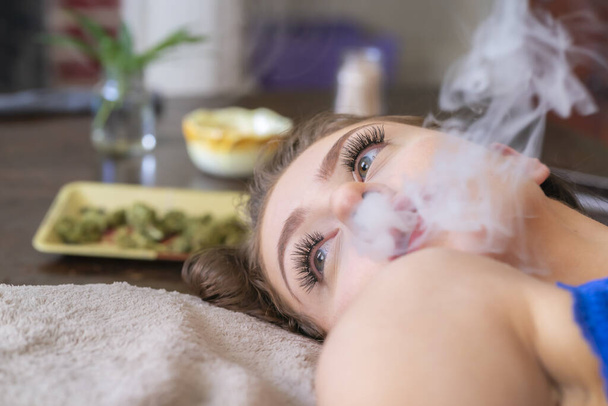 A beautiful brunette model smokes marijuana in the privacy of her own home - Zdjęcie, obraz