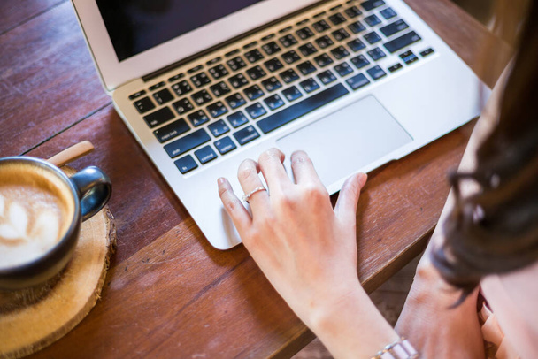 Горячий кофе латте с руками деловых женщин используют ноутбук на деревянном столе в кафе
 - Фото, изображение