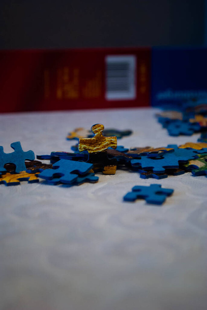 Close-up of colorful pieces of puzzle. One standing puzzle piece on the table. Stack of Puzzle Pieces. Puzzle pieces. Puzzle figures. Puzzle for fun.  - Photo, Image