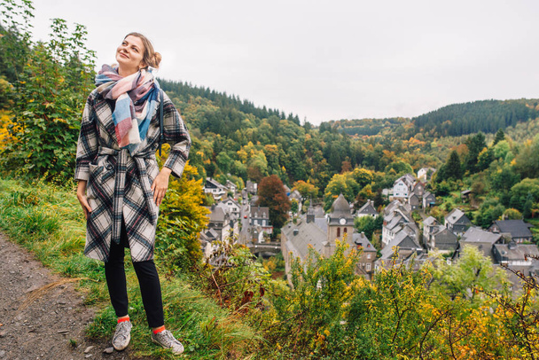 a girl in a coat stands against a panoramic view of Monschau, despite the wet weather.Germany - Фото, зображення