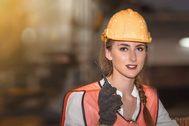 Jeune femme ingénieur avec talkie walkie sur fond d'usine flou
  - Photo, image