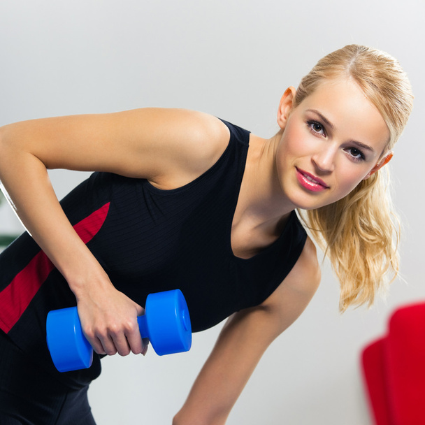 Young happy smiling woman with dumbbells, indoors - Fotografie, Obrázek
