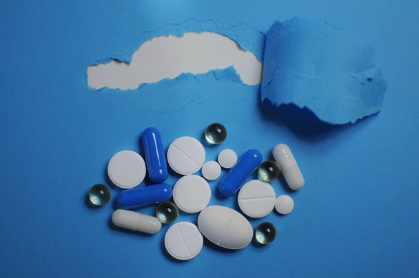 Monia eri pillereitä sinisellä pöydällä. Paljon värikkäitä eri pillereitä, mukaan lukien viruslääkkeet. Lääkkeet COVID-19:ää ja muita sairauksia vastaan
 - Valokuva, kuva