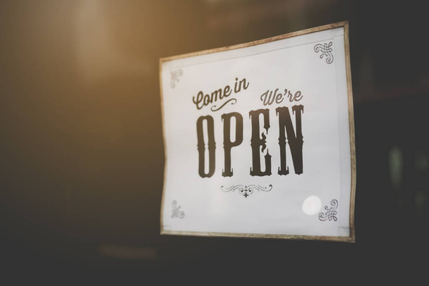 A business sign that says open on cafe or restaurant hang on door at entrance. Vintage color tone style. - Photo, Image