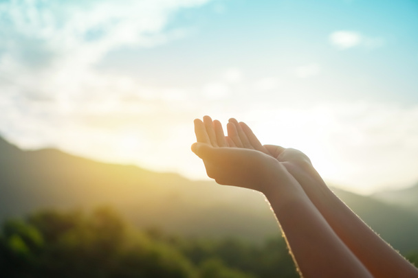 Woman hands place together like praying in front of nature green bokeh and blue sky  background. - Photo, Image