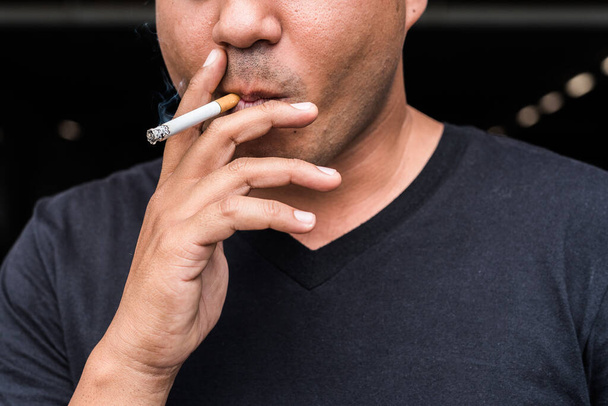 Κοντινό πλάνο νεαρός άνδρας καπνίζει ένα τσιγάρο. - Φωτογραφία, εικόνα