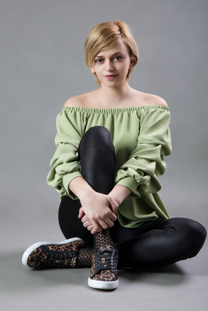 Porträt einer jungen Frau in grünem Hemd und schwarzer Leggings. Studioaufnahme einer jungen schönen Frau. - Foto, Bild