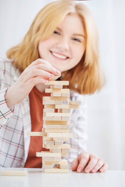 красива дівчина-підліток будує вежу з дерев'яних кубиків
 - Фото, зображення