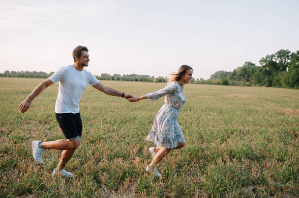 A girl and a guy are walking in the park. Portrait of a couple, a love story.Happy smiling, loveling couple together outstretched at beautiful nature. Lovestoty - 写真・画像