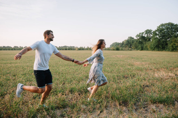 A girl and a guy are walking in the park. Portrait of a couple, a love story.Happy smiling, loveling couple together outstretched at beautiful nature. Lovestoty - Fotó, kép