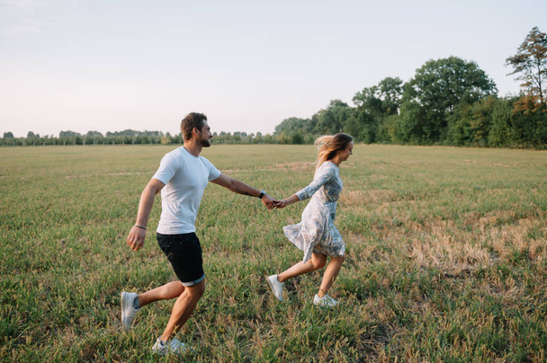A girl and a guy are walking in the park. Portrait of a couple, a love story.Happy smiling, loveling couple together outstretched at beautiful nature. Lovestoty - Foto, imagen