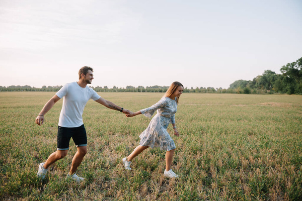 A girl and a guy are walking in the park. Portrait of a couple, a love story.Happy smiling, loveling couple together outstretched at beautiful nature. Lovestoty - Foto, afbeelding