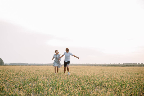 A girl and a guy are walking in the park. Portrait of a couple, a love story.Happy smiling, loveling couple together outstretched at beautiful nature. Lovestoty - Foto, Imagen