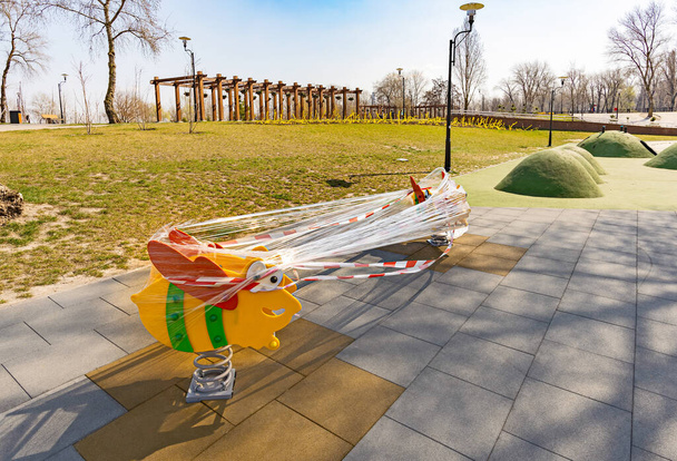 Children's playground, in Kiev, Ukraine, closed due to containment due to a coronavirus outbreak, covid-19. The games are wrapped in cellophane to prevent their use. - Photo, Image