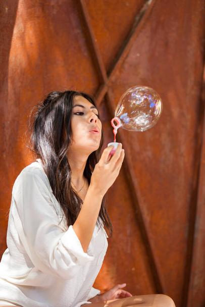 Krásná mladá žena s bílou halenkou foukání mýdlo bublina - Fotografie, Obrázek