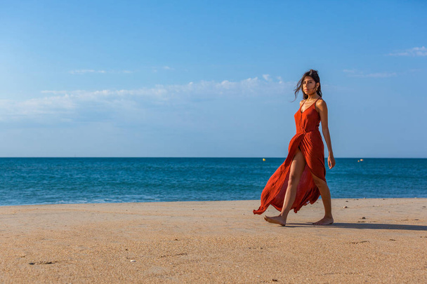 Jeune femme marchant pieds nus sur le sable de la plage. Concept de joie et de liberté
 - Photo, image