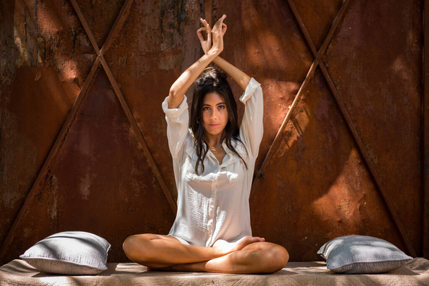 Jonge vrouw zit met gekruiste benen yoga te beoefenen in een tuin. innerlijke rust vinden. Positieve energie. Vrijheid. Ontspanning. Meditatie - Foto, afbeelding
