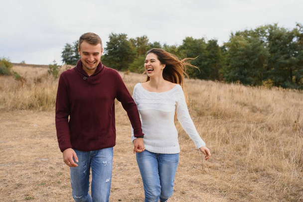 Beautiful young couple walking in autumn park - Zdjęcie, obraz