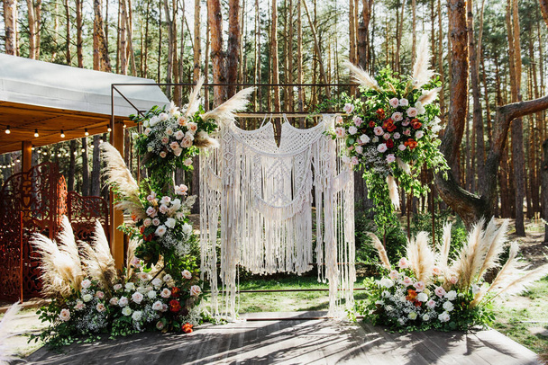Прекрасная свадебная церемония в лесу. Красивая арка в стиле фо украшена цветами и свечами
. - Фото, изображение