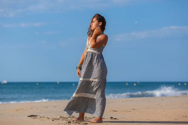 Hezká mladá žena v šatech a nahé nohy na písku pláže. Šťastná dívka těší svobodu na moři - Fotografie, Obrázek