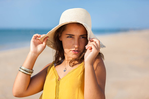Moda de retrato de mulher jovem bonita com chapéu de palha em uma praia no verão. Menina sorridente feliz
 - Foto, Imagem