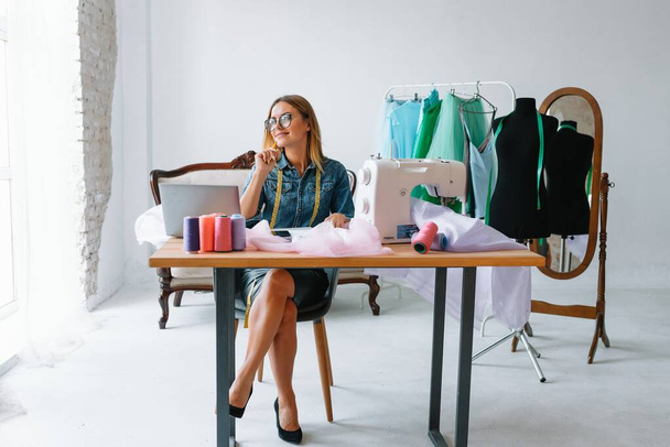 happy young fashion deisgner in her studio. concept of tailoring - Foto, Bild