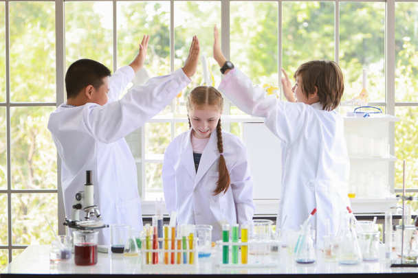 Bilim deneyleri yapan mutlu çocukların zafer sembolü. (başarı eğitimi veya bilim adamı konsepti) - Fotoğraf, Görsel