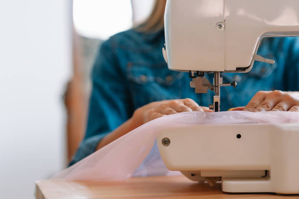 sewing machine, pink fabric and women's hands - 写真・画像