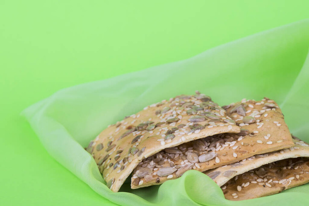 Sušenky na zeleném plátně. Dietní sušenky se semínky. Čtvercové cookies na zeleném pozadí - Fotografie, Obrázek