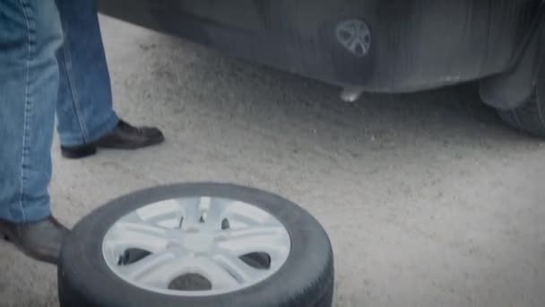 Bir adam kış lastiklerini yazla değiştirmek için bagajdan araba tekerleklerini indiriyor. - Video, Çekim