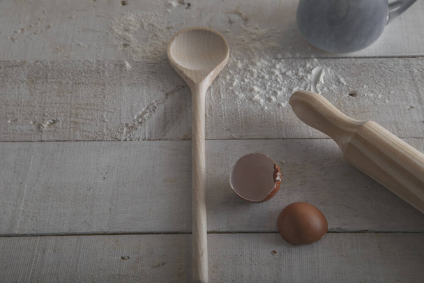Wooden spoon and rolling pin to make the dough, flour and egg. Preparation of the dough on white wooden background. Isolated image. Image from above - Фото, зображення