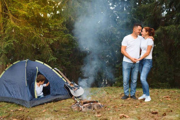 Romantic couple camping outdoors and sitting in a tent. Happy Man and woman on a romantic camping vacation. - Fotoğraf, Görsel