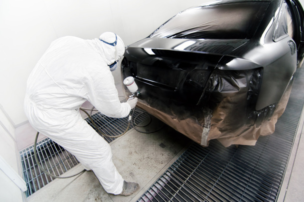 Worker painting a car in garage using an airbrush gun - Foto, imagen
