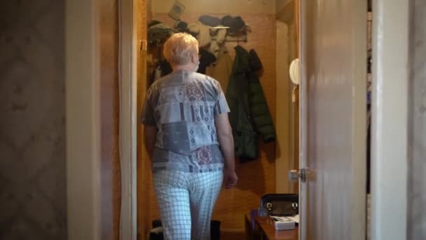 Η γιαγιά κοιτάει από το ματάκι της πόρτας. Περιμένει εθελοντές κατά τη διάρκεια της πανδημίας του COVID-19.. - Πλάνα, βίντεο
