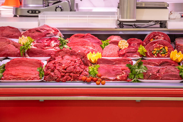 Meat department, showcase with variety of meat in different cuts. Inside an Italian supermarket. Different types of fresh meat arranged in an orderly manner. - 写真・画像