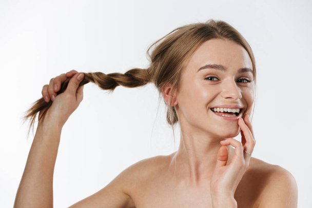 Beauty portrait of gorgeous young blonde half-naked woman smiling and holding her braid isolated over white background - Φωτογραφία, εικόνα