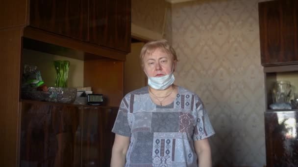 自宅でのコロナウイルスのパンデミックの間に彼女の顔にマスクをつけている祖母. - 映像、動画