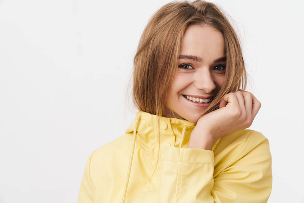 Photo closeup of funny young woman in raincoat looking at camera and smiling isolated over white background - Фото, изображение