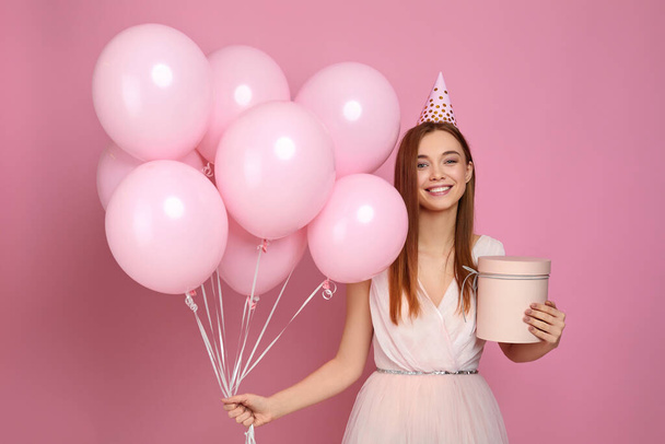 woman in birthday hat celebrating with pastel pink air balloons - Foto, Imagen