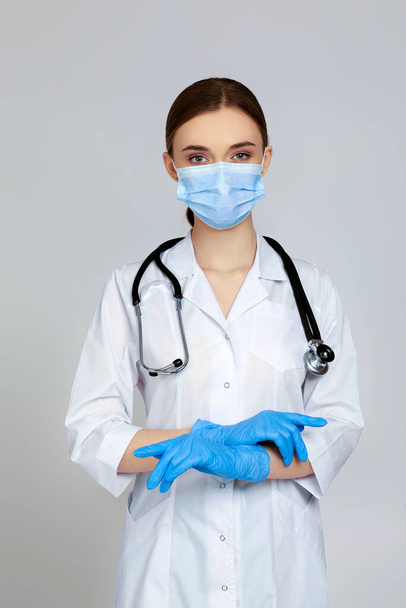Portrait of beautiful woman doctor in white lab coat and stethoscope isolated on gray background - Photo, image