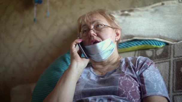 Η γιαγιά με τη μάσκα καλεί εθελοντές στο τηλέφωνο για παράδοση φαγητού. Ήταν σε αυτο-απομόνωση στο σπίτι κατά τη διάρκεια της πανδημίας του κορωναϊού.. - Πλάνα, βίντεο
