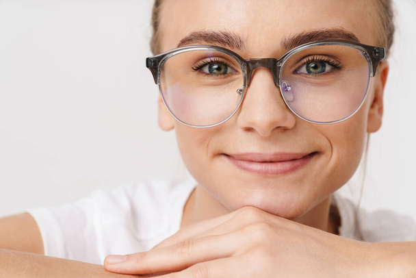 Photo of caucasian funny woman in eyeglasses smiling while leaning on table isolated over white background - Φωτογραφία, εικόνα