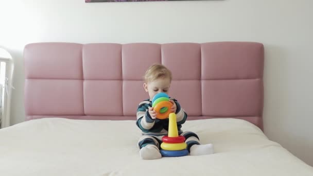 Een kleine jongen van een jaar heeft plezier. Gelukkig schattig jongen heeft plezier spelen kleurrijk speelgoed in huis woonkamer - Video