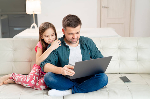 dad and daughter work online on laptop on couch. - Valokuva, kuva