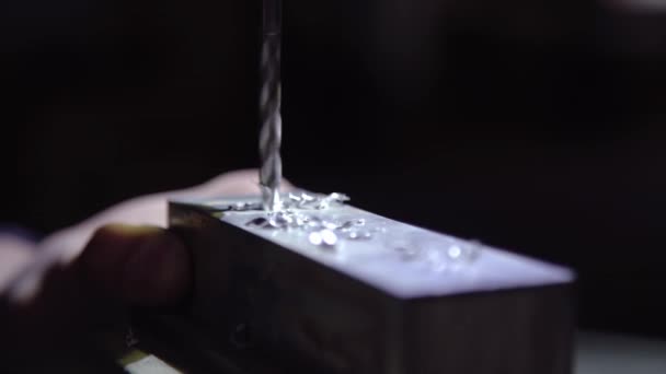 Διεστραμμένα κομμάτια περίσσειας μετάλλου πετούν από ένα κομμάτι αλουμινίου κατά τη διάρκεια της πλύσης με ένα CNC τρυπάνι. Λεπτός μύλος κοπής που ξυρίζει την πλευρά ενός ματ μπλοκ από μέταλλο. - Πλάνα, βίντεο