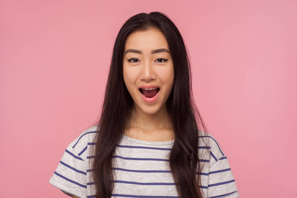 Wow, unbelievable story! Portrait of amazed girl with long brunette hair in striped t-shirt keeping her mouth opened and looking with surprised face. indoor studio shot isolated on pink background - Фото, зображення