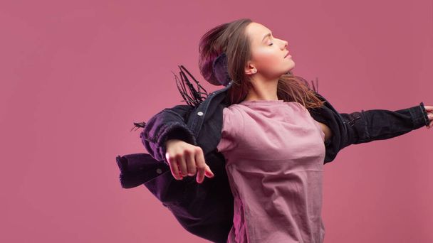 cheerful girl in a fringed jacket dances on a pink background. - Foto, Imagem