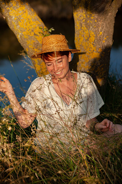 Αδιάβροχη, ξελαμπικαρισμένη, γυναίκα με ένα σιδερένιο καπέλο στο γρασίδι στο νεκροταφείο. - Φωτογραφία, εικόνα