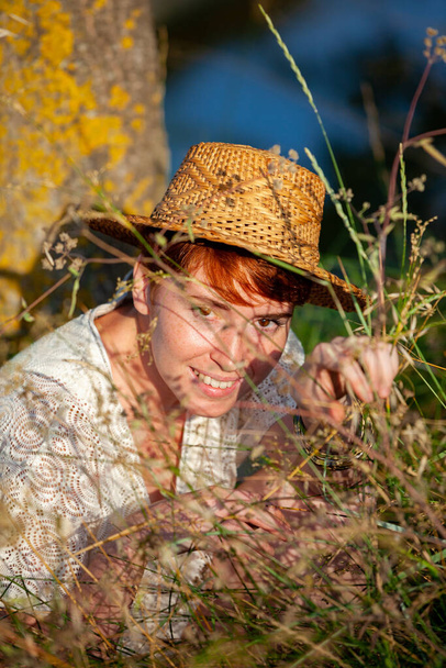 WELLNESS, RELAXATION, WOMAN WITH A STRAW HAT IN THE GRASS IN THE COUNTRYSID - Fotografie, Obrázek